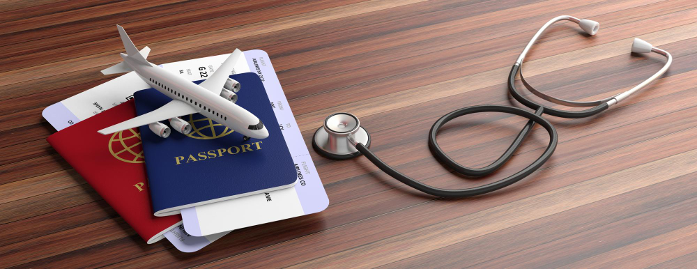 Small airplane a top pf a couple passports with a stethoscope next to them. Insurance abroad