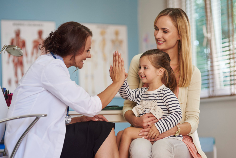 Pediatrician High giving a high five to her little patient while sitting on mom's lap.